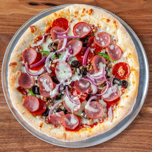A Verona Italian Cafe pizza with pepperoni, sausage, olives, onions, and green peppers on a metal tray.