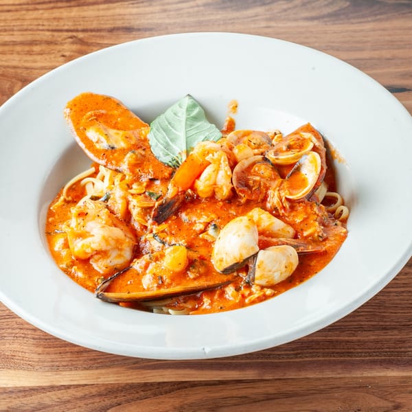 Seafood pasta with shrimp, clams, mussels, and squid in a rich red sauce, garnished with basil.